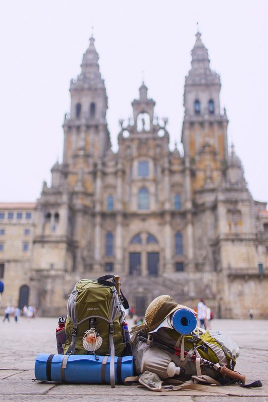 two backpacks sitting on the ground in front of a large building with a clock tower