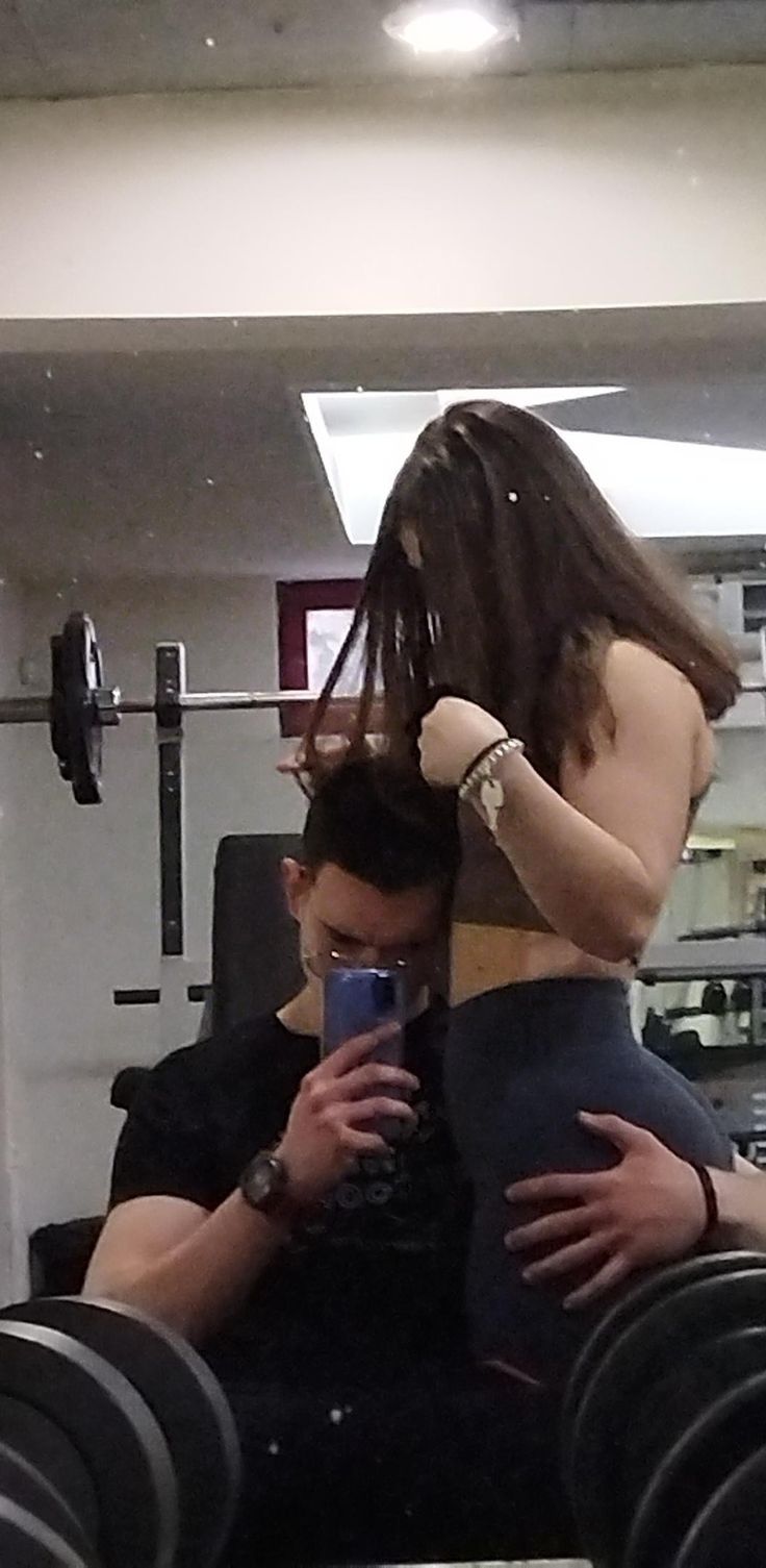 a man sitting on top of a woman's back while holding a cell phone