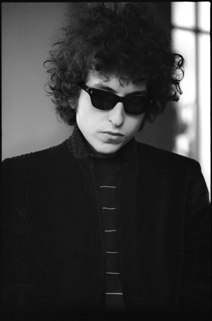 a young man with curly hair wearing sunglasses