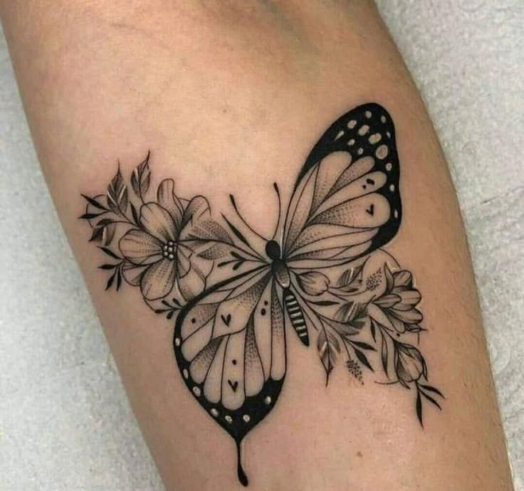 a black and white butterfly tattoo on the right leg, with flowers around its wings