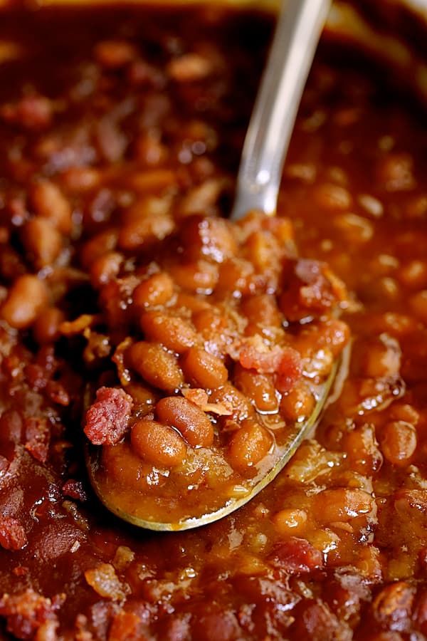 a spoon full of beans and bacon in a bowl