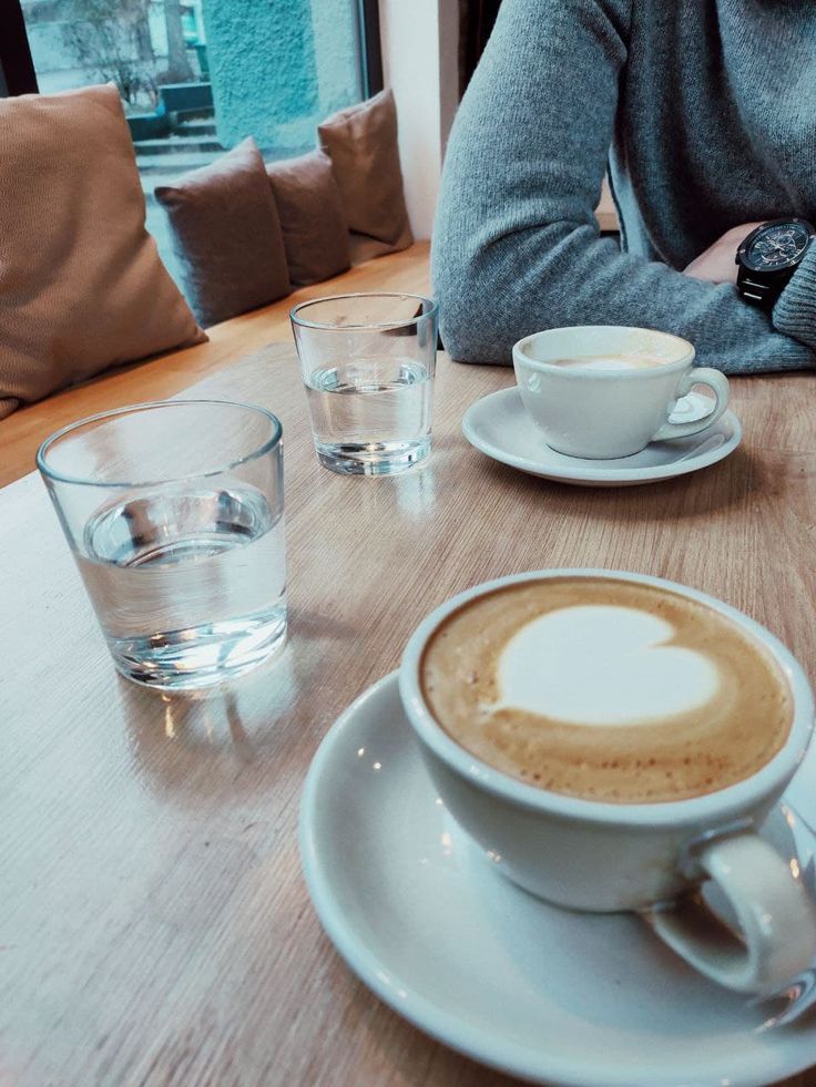 a person sitting at a table with a cappuccino in front of them