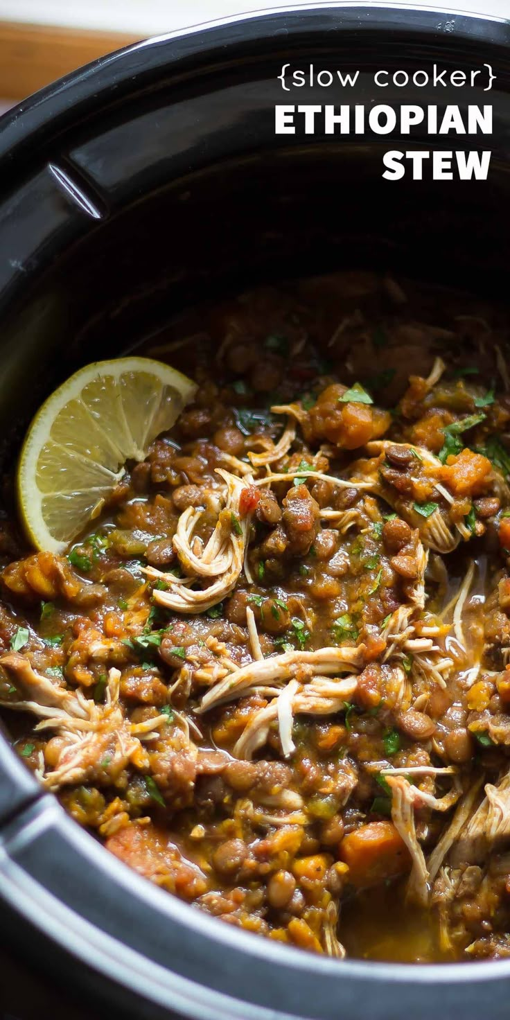 a slow cooker filled with stew and garnished with cilantro, lemon wedges and parsley