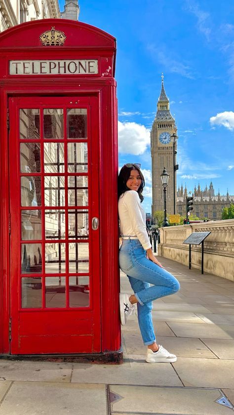 a woman leaning against a red phone booth