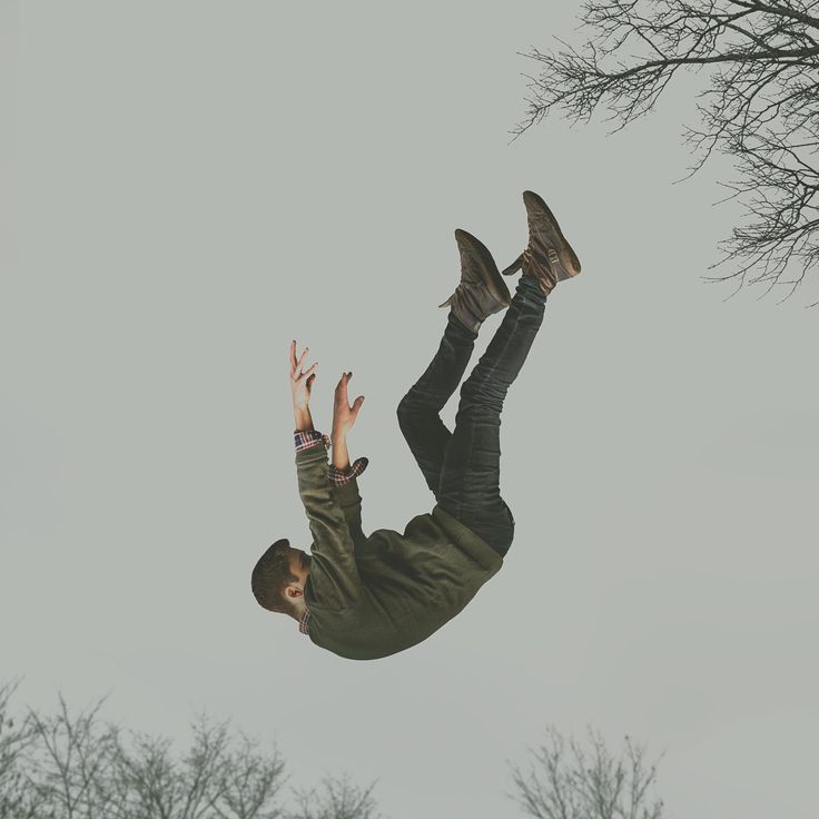 a man flying through the air while riding on top of a skateboard in front of trees