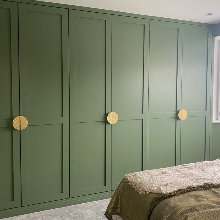 a bedroom with green painted walls and gold knobs on the doors, along with a bed