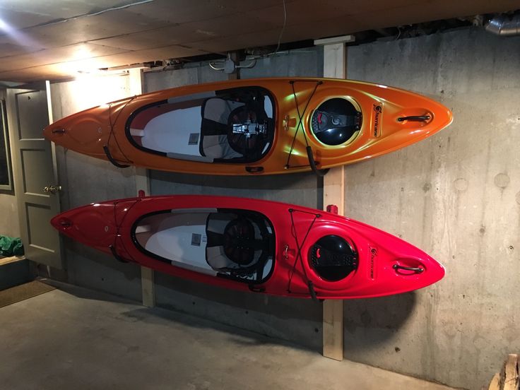 two kayaks are mounted to the wall in a garage, one red and one orange