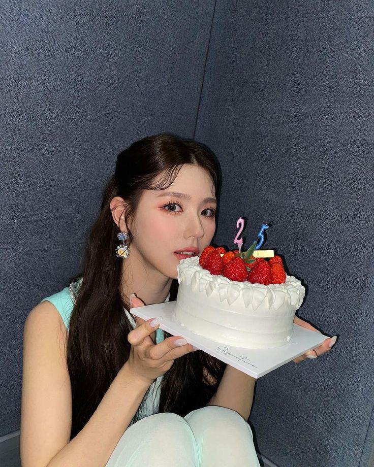 a woman sitting in front of a cake with candles on it and strawberries sticking out of the top