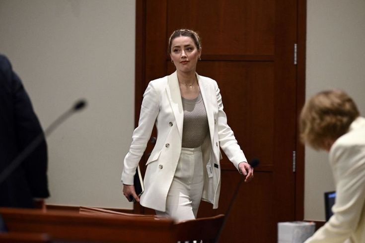 a woman standing in front of a microphone at a courtroom with another person behind her