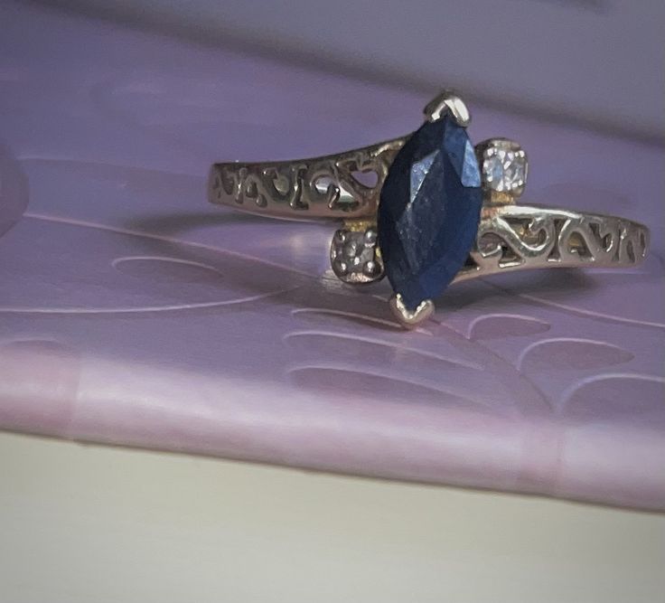 a ring with a blue stone on it sitting on top of a purple tablecloth