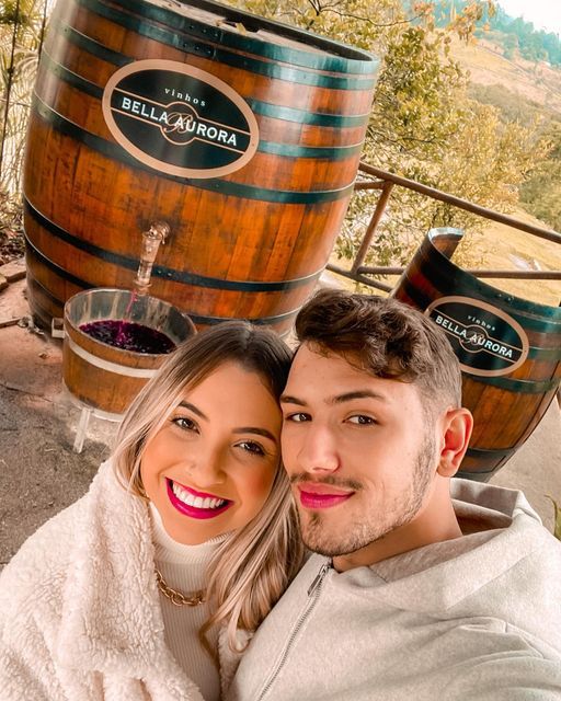 a man and woman taking a selfie in front of some barrels with wine on them