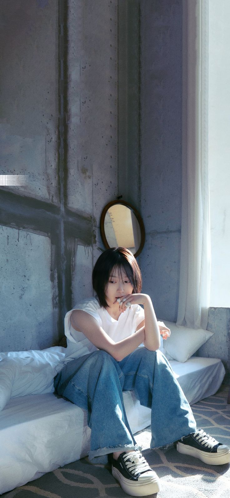 a woman sitting on top of a bed next to a wall with a mirror above her head