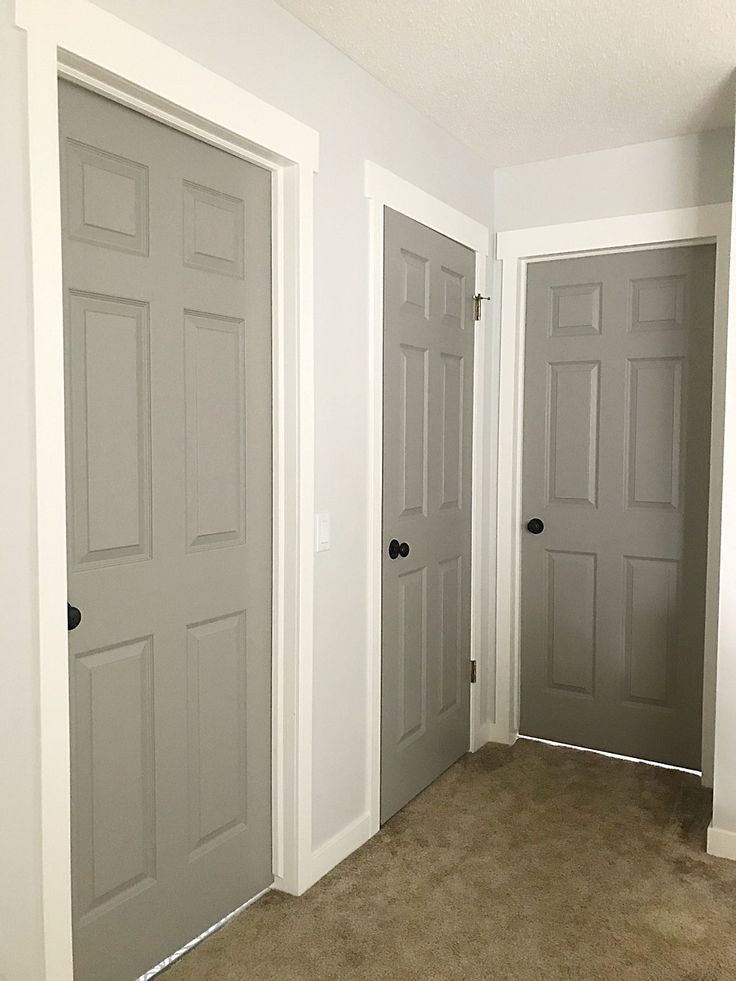 three doors in a room with carpeted flooring and two walls painted white, one is empty