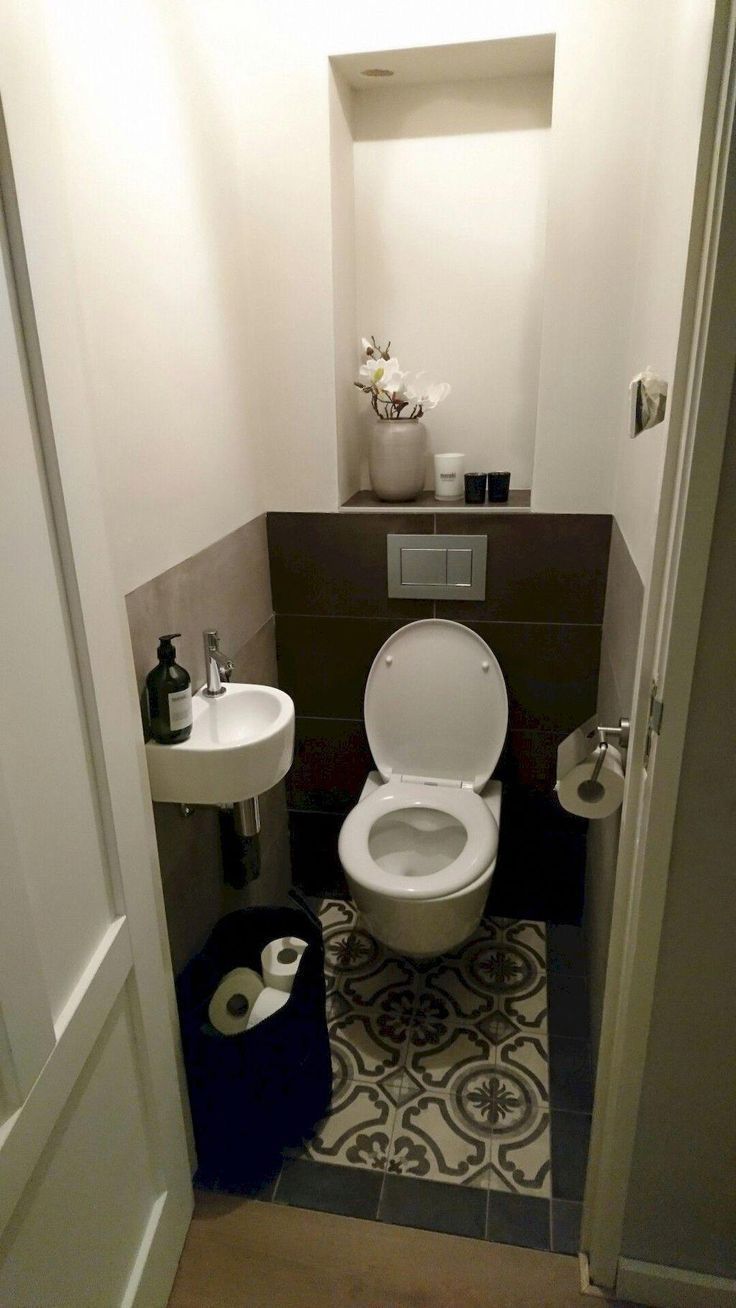 a bathroom with a toilet, sink and trash can in it's stall next to the door