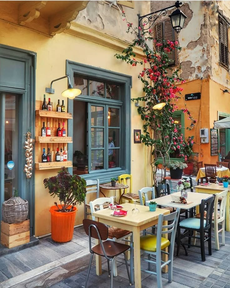 an outdoor dining area with tables and chairs, potted plants on the outside wall