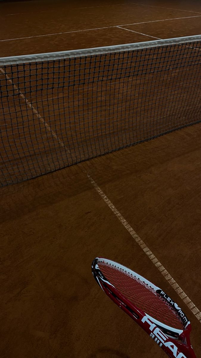 a tennis racket is on the ground in front of a net at night time