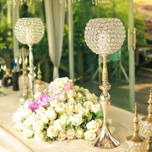 a table topped with lots of vases filled with white flowers and crystal candlesticks