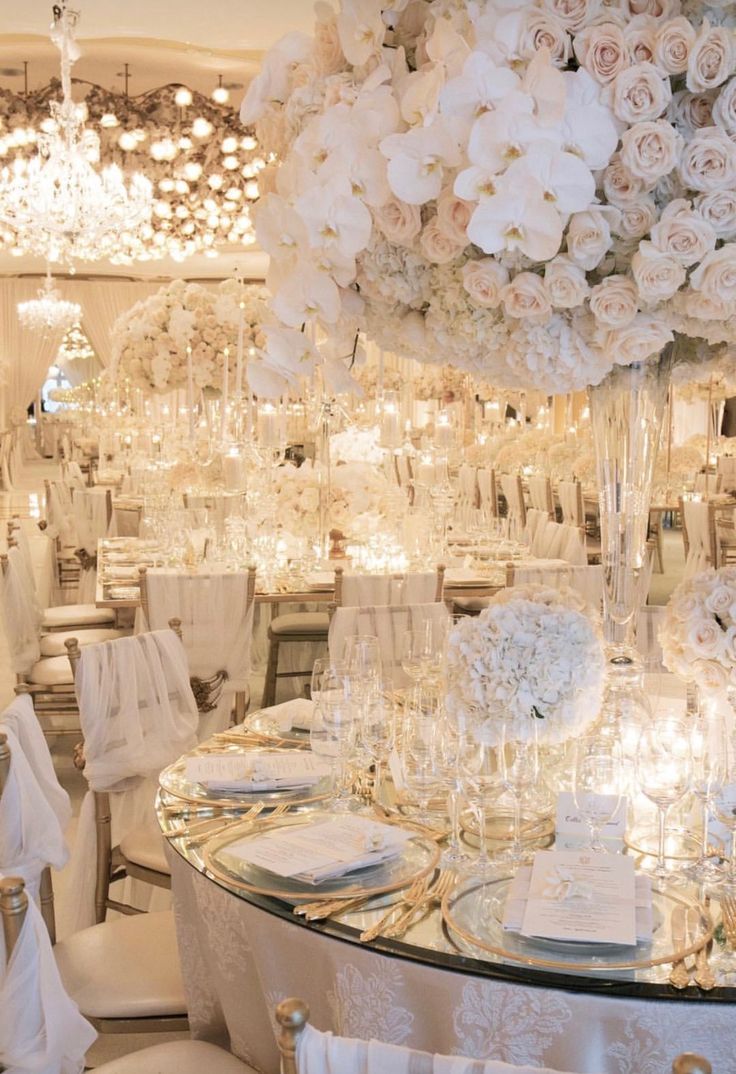 the table is set with white flowers and place settings for guests to sit down at