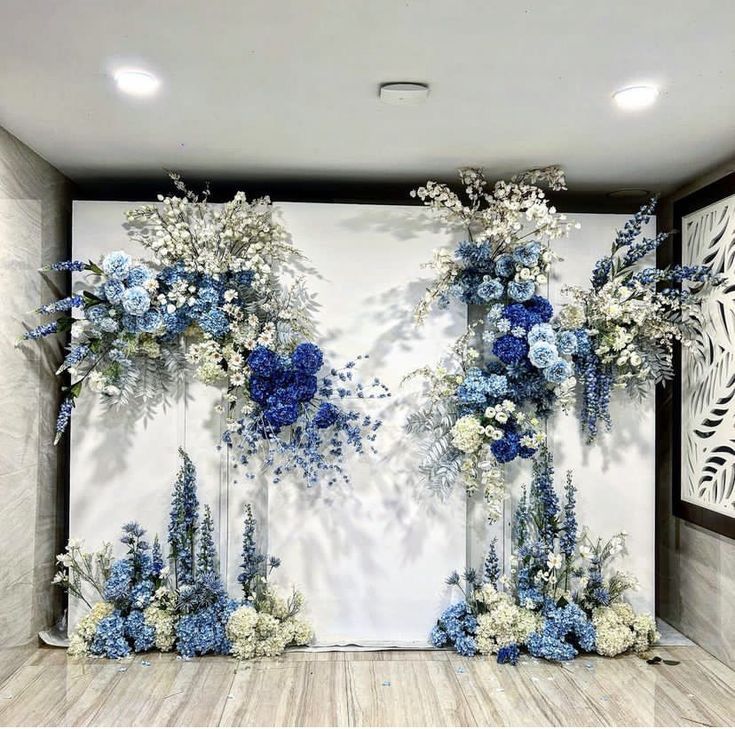 an arrangement of blue and white flowers in vases next to a large wall mural