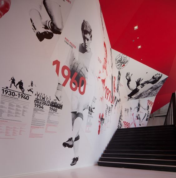 the wall is decorated with many different sports related images and numbers, along with black stairs