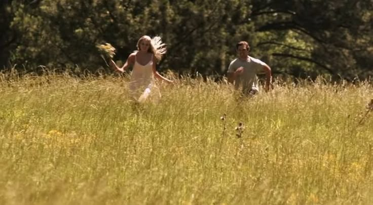 two people are running through the tall grass