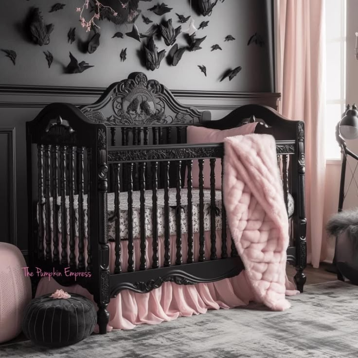 a black crib with pink sheets and pillows in a room decorated with bats on the wall