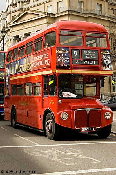 two red double decker buses driving down the street