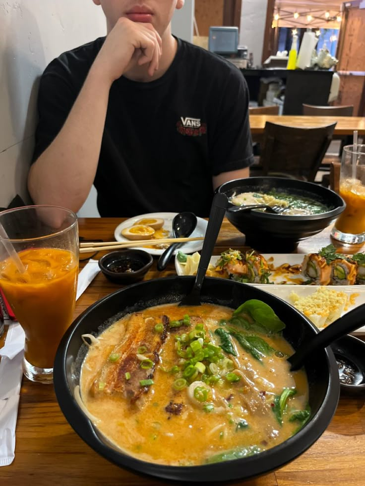 a man sitting at a table in front of a bowl of soup and orange juice