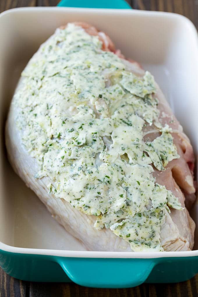 a piece of chicken covered in parmesan cheese and herbs sitting in a blue casserole dish