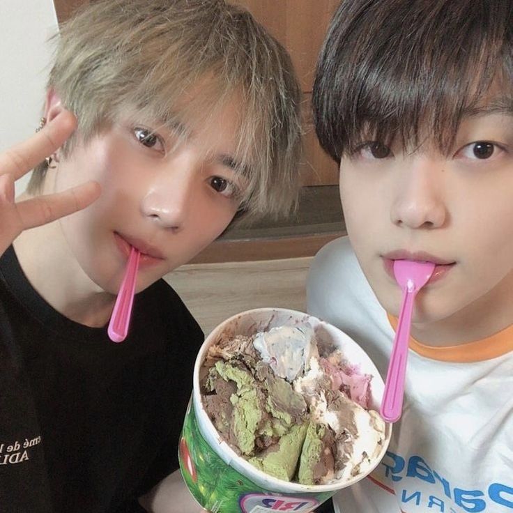 two young boys are eating ice cream and drinking pink straws while posing for the camera