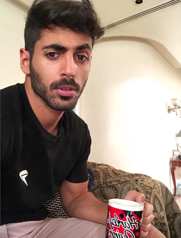 a man sitting on a couch with a cup in his hand and looking at the camera