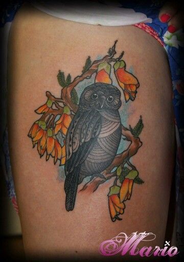 an owl tattoo on the back of a woman's thigh, with leaves and flowers around it