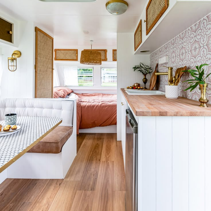 a kitchen and dining area in a mobile home with wood flooring, white walls and cabinets