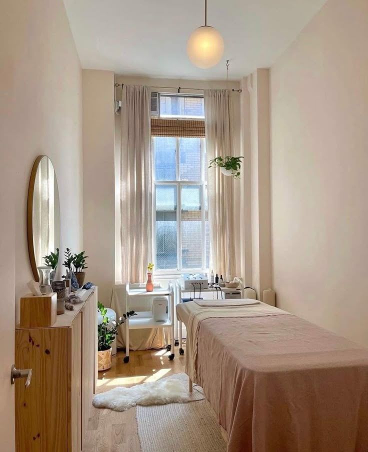 a bedroom with a bed, dresser and mirror in it's corner next to a window