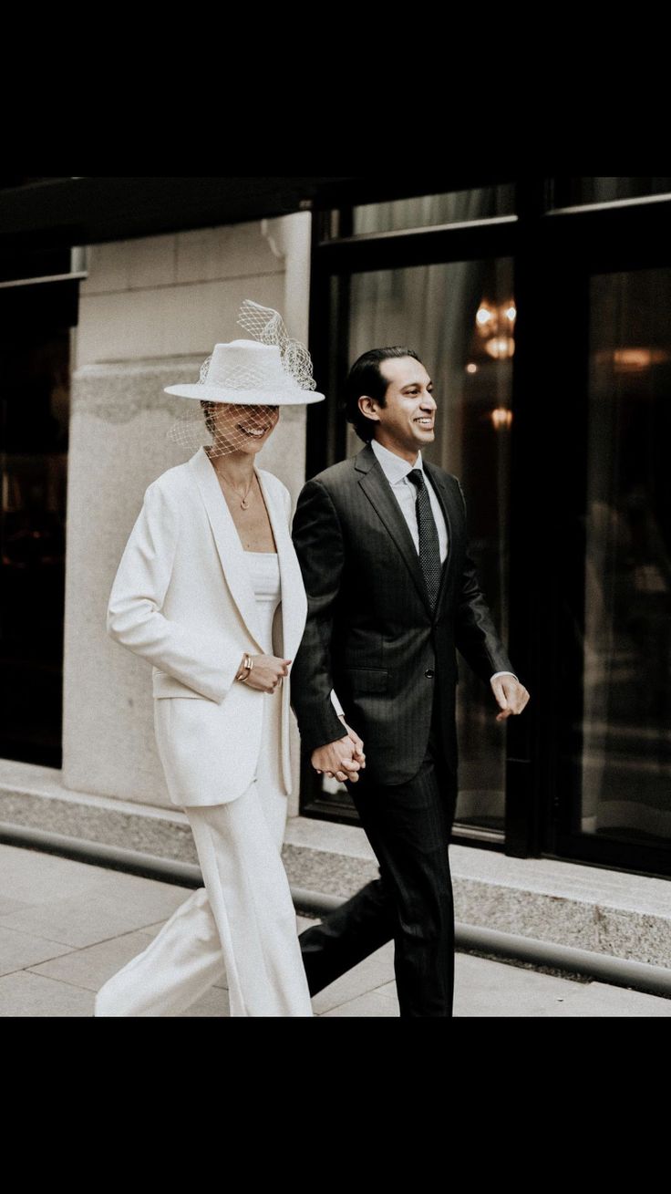 a man and woman dressed in white walking down the street