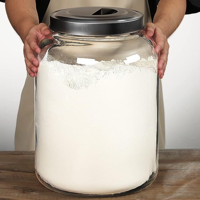 a person in an apron is holding a large jar with white flour on the lid