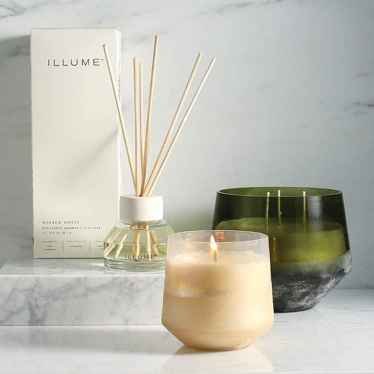 two candles and a box sitting on a table next to each other in front of a candle holder