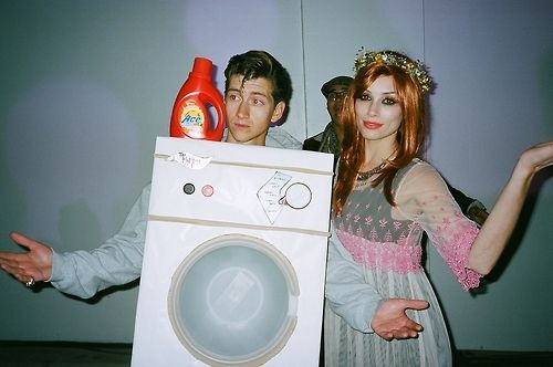 a man and woman dressed up in costumes holding a washing machine with the door open