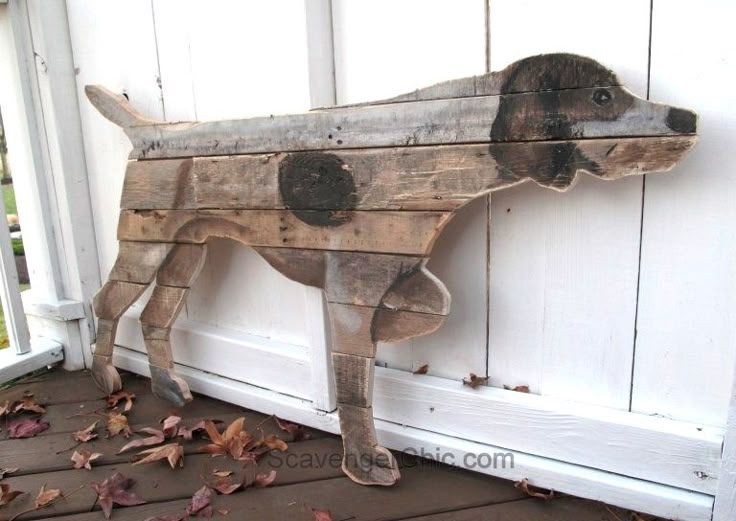 a dog made out of wooden planks sitting on the ground next to a door