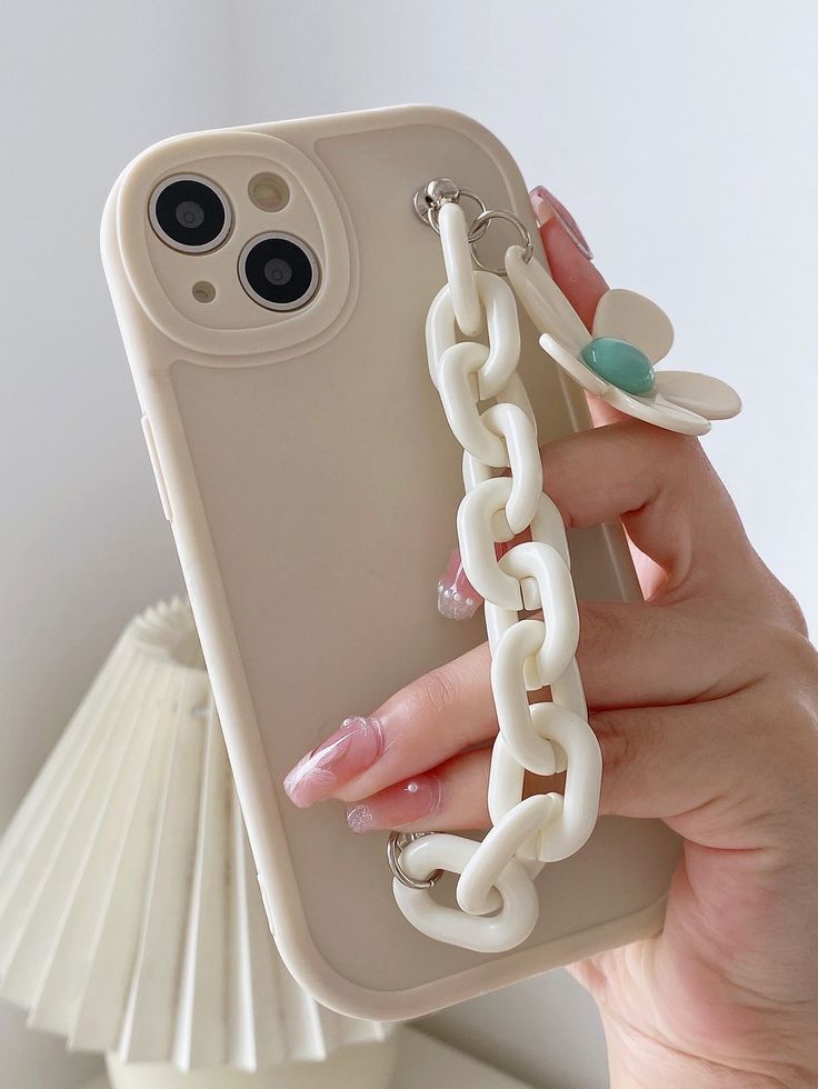 a woman's hand holding an iphone case with chains attached to it