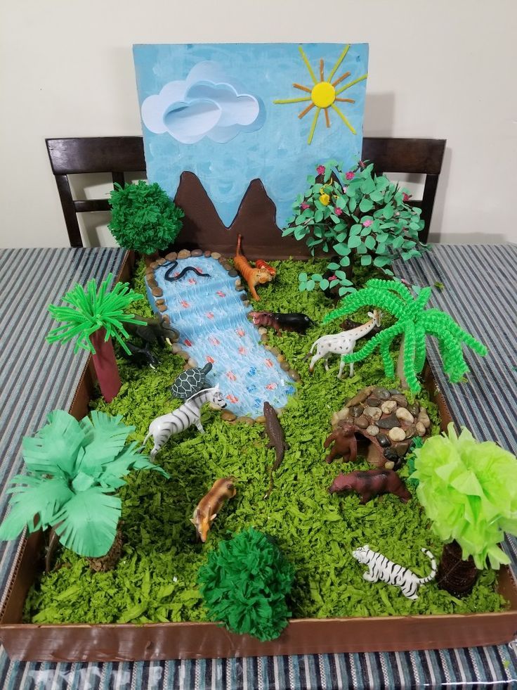 a table topped with lots of fake plants and animals on top of green moss covered ground