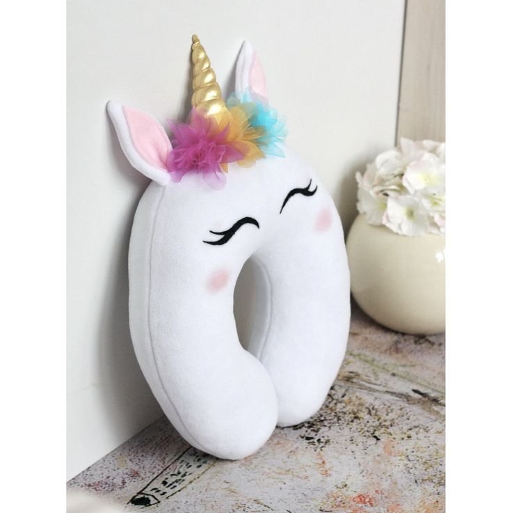 a stuffed unicorn is sitting next to a white wall