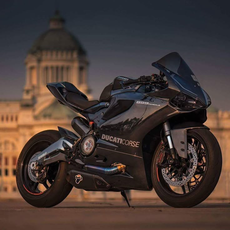 a black motorcycle parked in front of a large building with a dome on it's roof