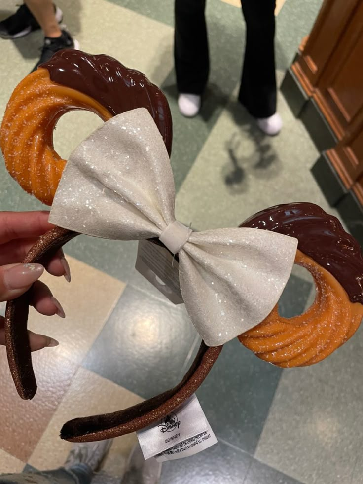 a person is holding up a mickey mouse ears with chocolate and pretzels on it