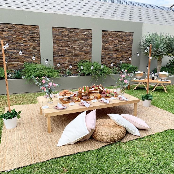 a picnic table with food on it in the middle of a grass area next to some plants