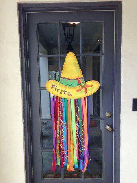 a door with a sign that says fiesta hanging from it's side and a hat on top