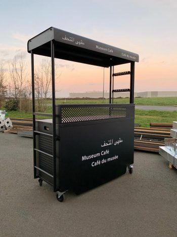 a food cart sitting in the middle of a parking lot next to some wooden benches