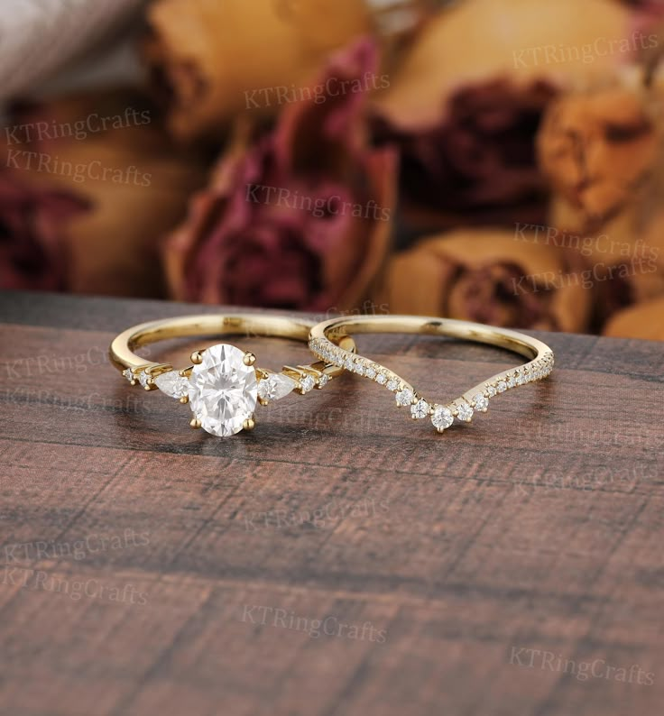 two gold rings with diamonds on top of a wooden table