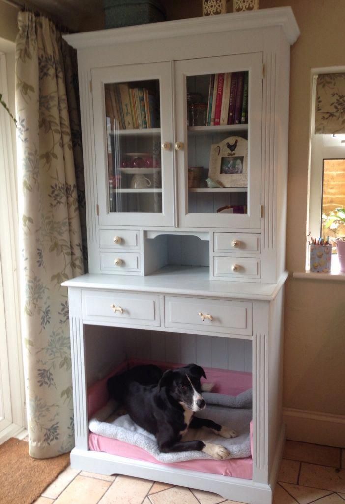 a black and white dog laying on top of a bed under a cabinet