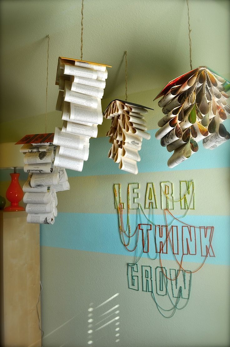 some paper birds hanging from the ceiling in front of a blue and white striped wall